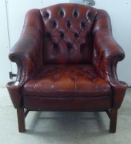 A 20thC buttoned red fabric upholstered enclosed armchair, raised on square forelegs