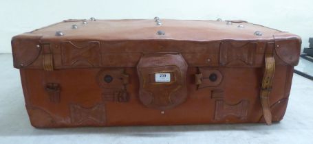 A brown hide case with strap and stud ornament  12"h  30"w