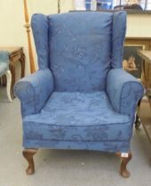 A modern blue fabric upholstered wingback armchair, raised on cabriole legs