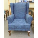 A modern blue fabric upholstered wingback armchair, raised on cabriole legs