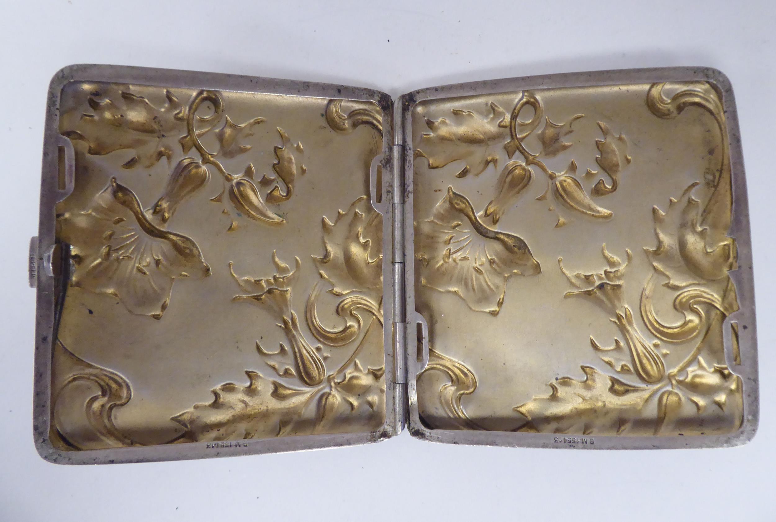 An Art Nouveau silver coloured metal, folding cigarette case, on a button clasp, embossed and chased - Image 2 of 3