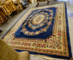 A Chinese washed woollen rug with floral motifs, on a cream coloured ground  105" x 150"