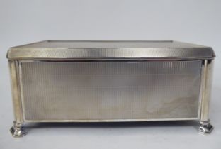 A silver engine turned cigarette box with chamfered corners, straight sides and a hinged lid,