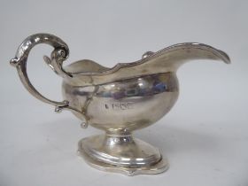 An Edwardian silver sauce boat of oval pedestal form with opposing loop handles and pouring lips