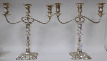 A pair of Georgian style, two-part silver candelabra, each comprising a central socket and two