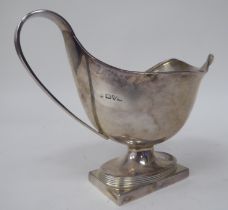A silver pedestal sauce boat with an applied wire rim and swept loop handle, on a rectangular