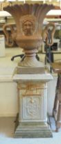 A cast iron terrace urn with a flared rim, opposing ring handles and masks, on a pedestal foot  30"h