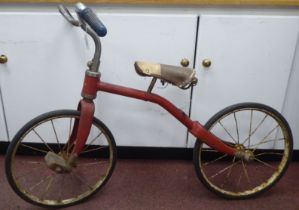 A child's vintage Tri-ang bicycle with a red painted frame and downswept handlebars, the pedals