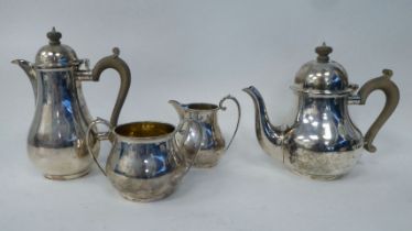 A four piece silver pear shape tea set, comprising a teapot and hot water pot with carved wooden