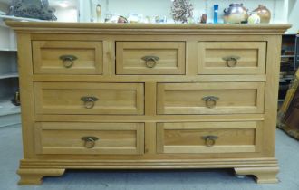 A modern light oak dresser, comprising an arrangement of seven drawers with brass ring handles,