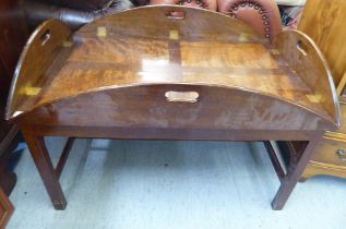 A mid 20thC military design, brass hinged, mahogany tray table, the base raised on square legs  18"h