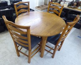 A modern oak table, raised on block legs  30"h  42"dia; and a matching set of four oak ladderback