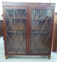A mid 20thC mahogany finished bookcase, the shelved interior enclosed by a pair of diamond glazed