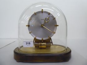 A Kundo Electromagnetic mantel clock; the exposed movement faced by a baton dial  9"h under a
