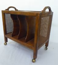 A modern walnut finished magazine rack with twin cut-out handles and woven split cane panels,