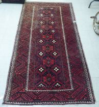 A Persian rug with floral motifs, on a red ground  44" x 82"