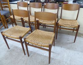 A set of six 1970s teak framed panelled back dining chairs, the woven cane seats raised on turned