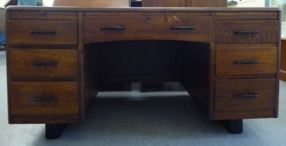 A mid 20thC stained oak twin pedestal desk, comprising an arrangement of seven drawers and two