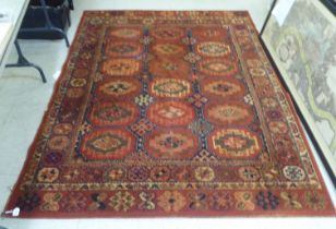 A Persian design rug, decorated with three columns of guls and geometric patterns, on a red