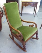 A late Victorian mahogany showwood framed, open arm rocking chair, upholstered in green fabric