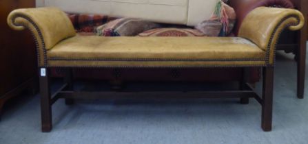An early 20thC window seat, stud upholstered in sun bleached brown hide, raised on square legs  54"w