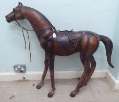 A burnished and moulded hide standing, saddled and bridled model horse  approx. 37"h