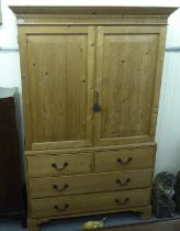 A modern pine linen press with a cornice, over two doors, two short/two long drawers, raised on