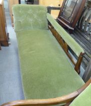 An Edwardian style stained beech framed and green part-button upholstered chaise longue, raised on