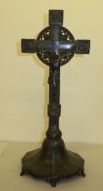 A cast metal freestanding crucifix, decorated with floral designs and bearing the inscription