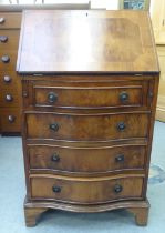 A lady's modern yewwood finished and string inlaid bow front desk, the fall flap with a scriber