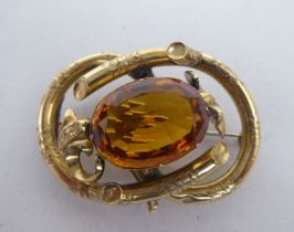 An antique engraved gold coloured metal brooch, set with an amber coloured stone