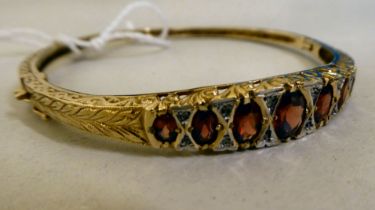 A 9ct gold hinged bangle, set with diamonds and garnets