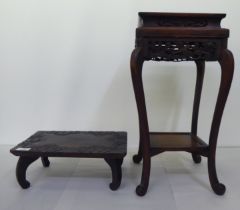 An early 20thC Chinese carved hardwood vase stand with an undershelf, raised on scrolled, cabriole