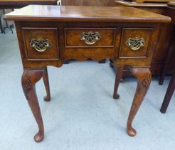 A Georgian style walnut veneered lowboy with a burr veneered and string inlaid top, over three