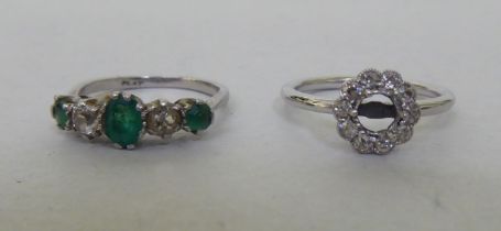 A platinum ring, set with alternating diamonds and emeralds; and another white metal floral design