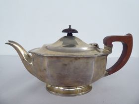 A silver teapot of panelled, oval, octagonal form with a swept spout, insulated handle and knop on
