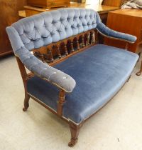 An Edwardian mahogany showwood framed salon settee with a curved back and open arms, part button
