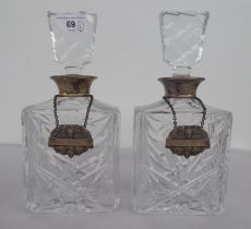 A pair of silver coloured clear glass decanters of shouldered, box design with silver decanter