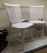 A set of four modern, off-white painted spindle back dining chairs, the solid seats raised on turned