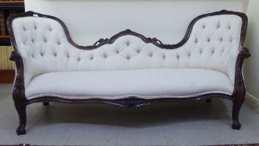 A mid Victorian rosewood framed double spoonback settee, upholstered in a cream coloured fabric,