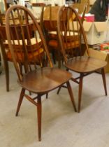 Two Ercol dark stained beech and elm framed spindle back chairs, the solid seats raised on