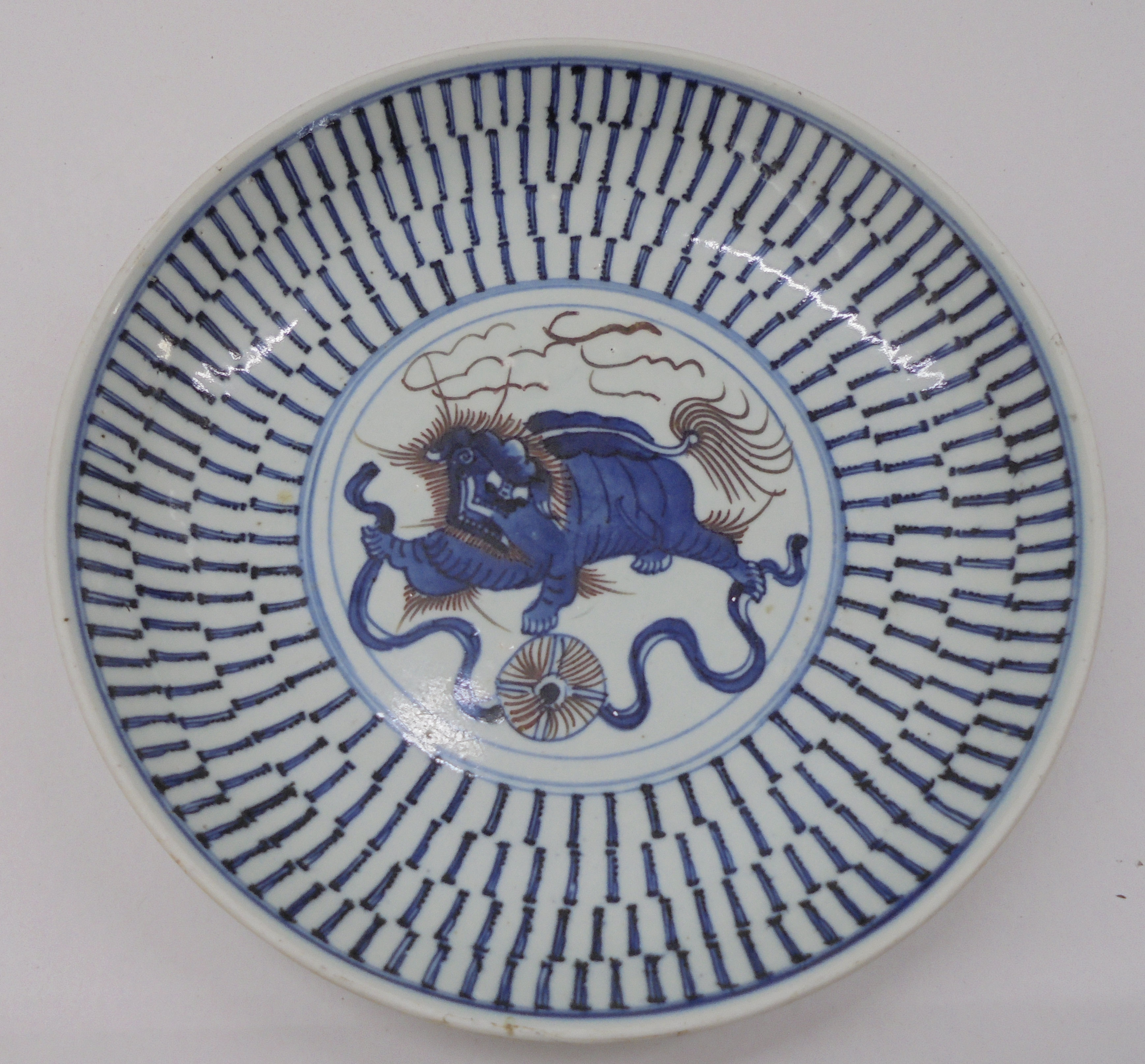 A 19thC Chinese provincial footed porcelain dish, decorated in blue, brown and white with a dragon-