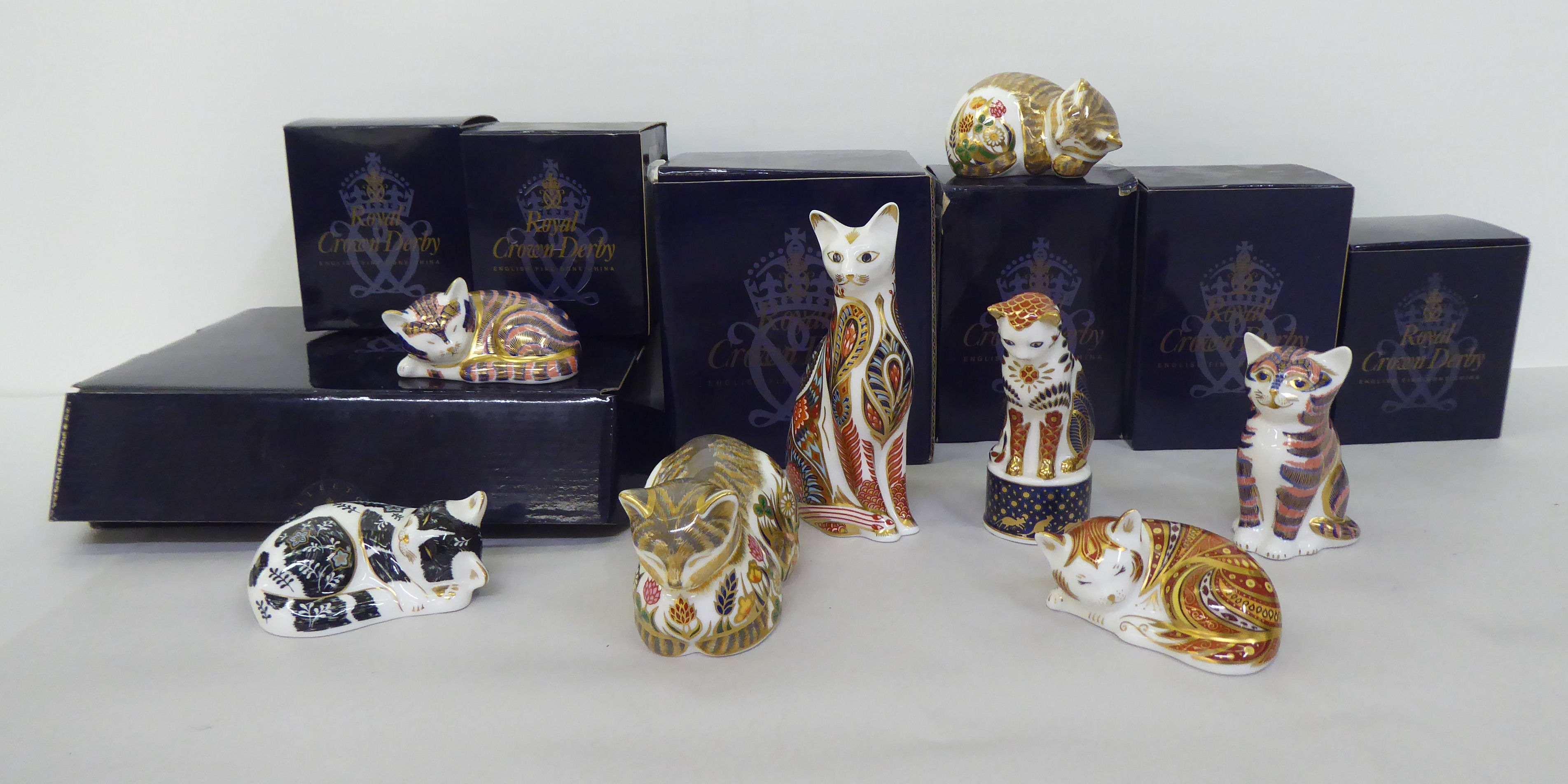 One Royal Worcester and six Royal Crown Derby china model cats, one with a silver stopper, the other