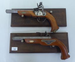 A pair of replica 19thC style duelling pistols, on display plinths