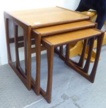 A nesting set of three 1970s G-Plan teak tables, designed by R Bennett, raised on open