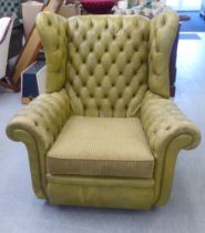 A modern Chesterfield enclosed armchair, upholstered in green simulated hide, on casters