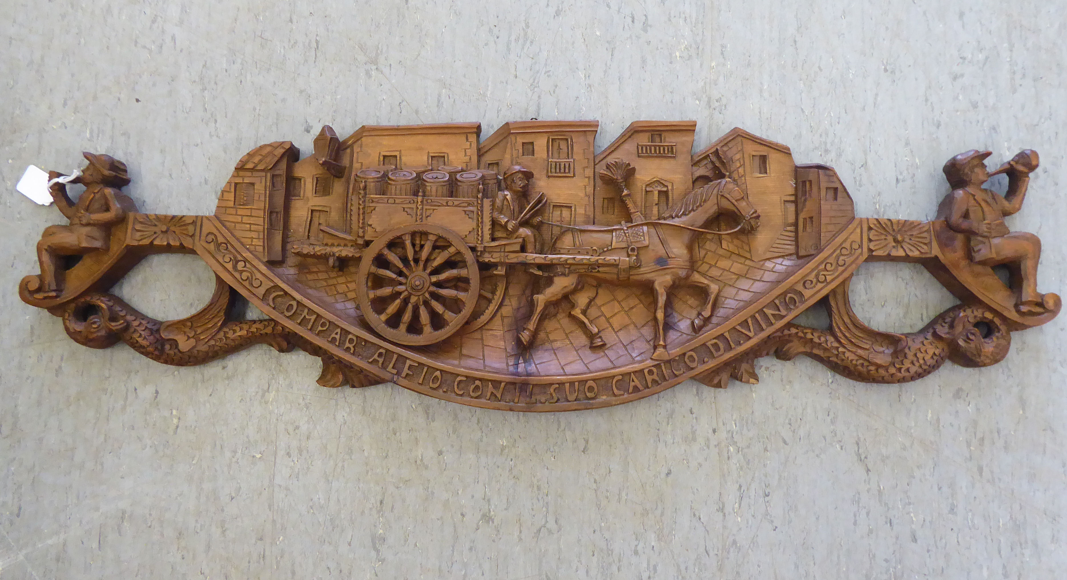 An Italian carved and stained softwood wall plaque, featuring a wine wagon and associated figures