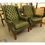 A pair of modern faux green button upholstered hide wingback library chairs, raised on block feet