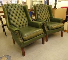 A pair of modern faux green button upholstered hide wingback library chairs, raised on block feet