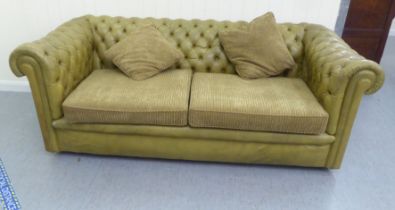 A modern two person Chesterfield settee, part button upholstered in green simulated hide, on casters